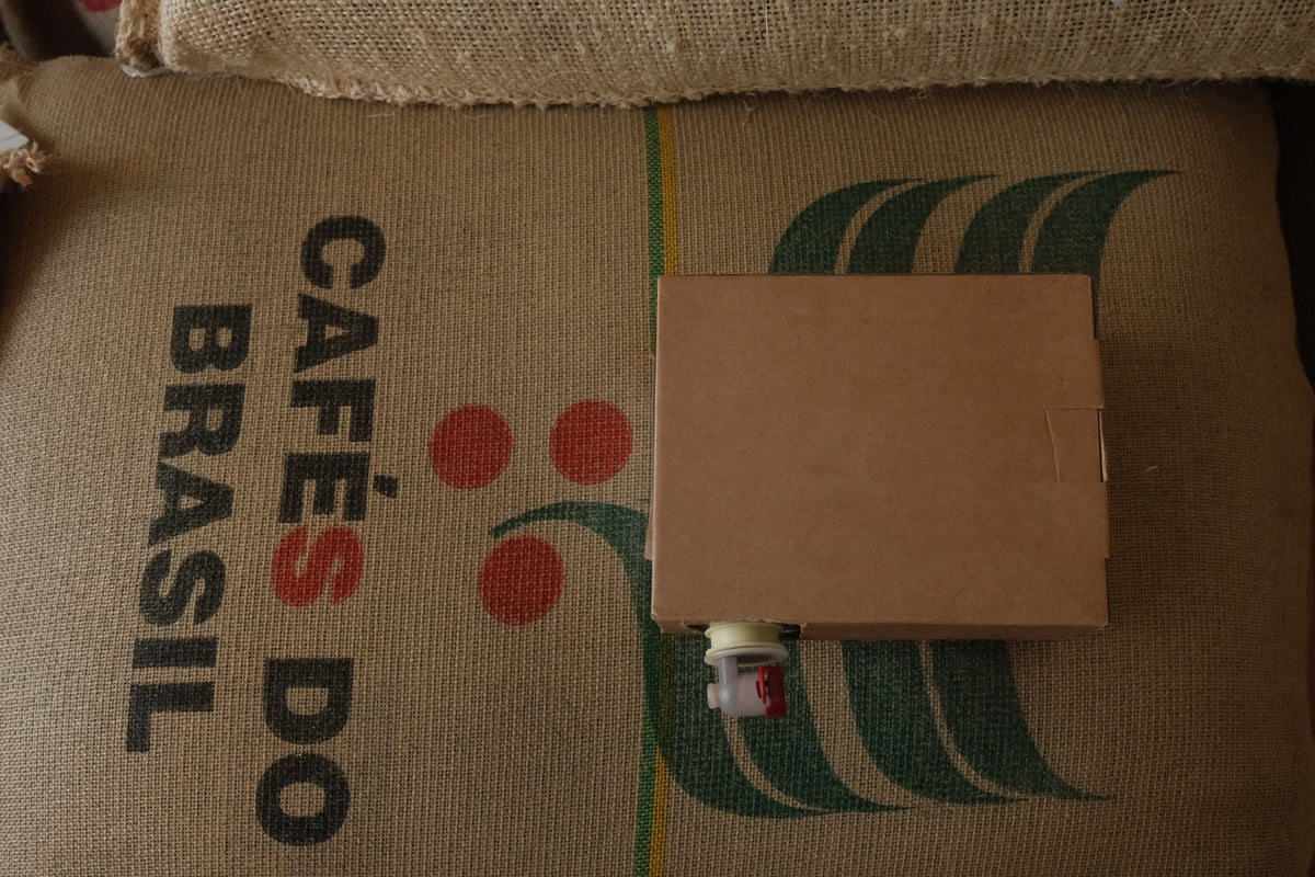 A box of coffee concentrate sat on top of a bag of specialty Brazilian coffee 