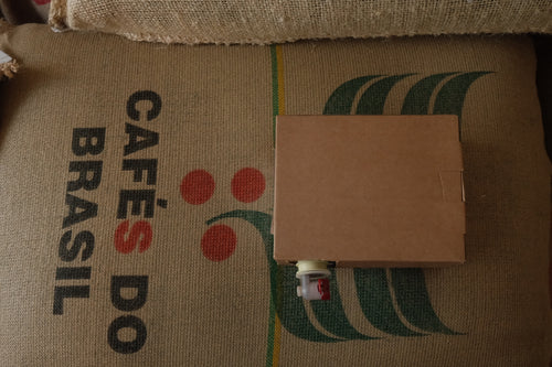 A box of coffee concentrate sat on top of a bag of specialty Brazilian coffee 